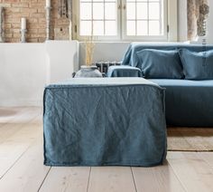 a living room with blue couches and pillows on the floor, next to a brick wall