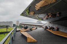 people are sitting on benches in front of a large building with an open area for eating and drinking