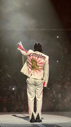 a man in a white suit standing on top of a stage