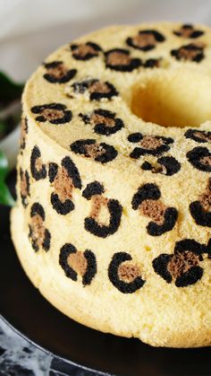 a cake with leopard print on it sitting on top of a black plate next to green leaves