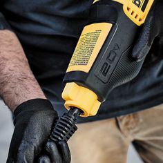 a man in black gloves holding a yellow and black drill