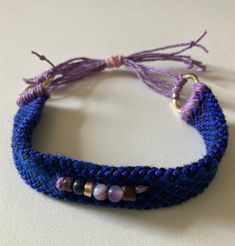 a close up of a bracelet on a white surface with beads and tassels