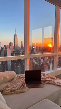 an open laptop computer sitting on top of a bed in front of a large window