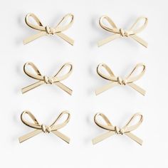 four pairs of gold bow clips on white background