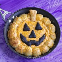 a pumpkin pie with googly eyes and mustaches in a cast iron skillet