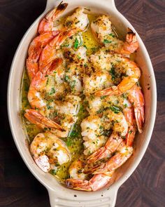 cooked shrimp in a white casserole dish with parsley and garlic on top