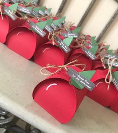 red apples with green leaves and tags on them are sitting on a table in front of a window