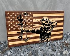 a wooden sign with an image of a man holding a bow and arrow in front of the american flag