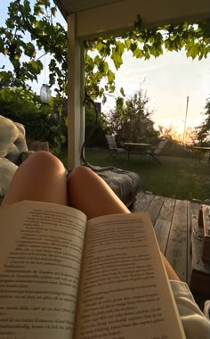 a person laying in a hammock with their legs crossed and reading a book