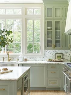 a kitchen with green cabinets and marble counter tops