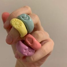 a hand holding three small toy items in it's palm, with the fingers pointing towards them