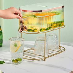 a person pours a drink into two glasses on a table with ice cubes