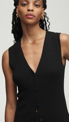 Elevate your workwear with a classic knit rib waistcoat. Designed to be worn as a top on its own or styled over a shirt or blouse, our waistcoat reimagines traditional suiting for the modern working woman. The slim silhouette features an all over ribbed pattern, a fitted v-neck silhouette, and button closure. Wear with relaxed trousers and sneakers for a cozy yet put-together ensemble. Ribbed Sweater Vest For Workwear In Fall, Classic Black Sweater Vest For Spring, Versatile Fitted Sweater Vest For Work, Fitted Versatile Sweater Vest For Workwear, Classic Sleeveless Cardigan For Work, Closet Revamp, Waistcoat Woman, Relaxed Trousers, Style Reference