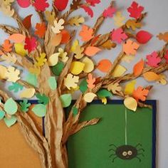 a paper tree with leaves and a spider hanging from it's trunk on a bulletin board