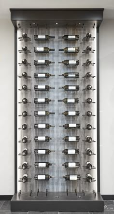 a wine rack with many bottles on it in front of a white wall and black tile floor