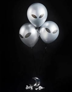 three balloons with faces on them in the dark