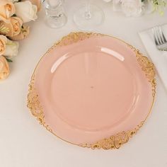 a pink and gold plate sitting on top of a table next to white napkins