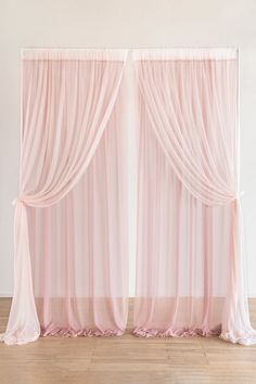 two pink drapes hanging on the side of a wall next to a wooden floor