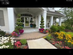 a house with lots of flowers and plants in front of the entrance to the house