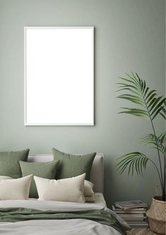 a bedroom with green walls and a white frame hanging on the wall next to a bed