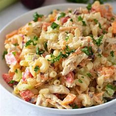 a white bowl filled with macaroni salad and garnished with parsley