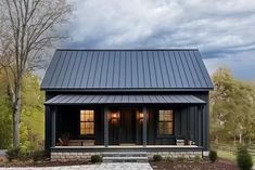 a small black house with two windows and a porch