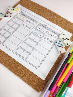 a cork bulletin board with dices and pencils on it next to some markers