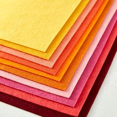 a stack of colored papers sitting on top of a white table next to each other