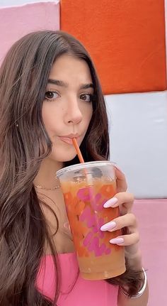 a woman in a pink dress drinking out of a plastic cup with a straw and sprinkles on it