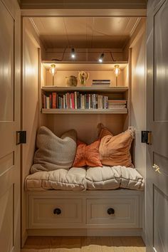 a room with some bookshelves and pillows on the bench in front of it