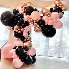 black, pink and gold balloons are arranged in the shape of a letter on a wall