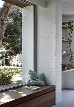 a window sill sitting next to a wooden bench in front of a white brick wall