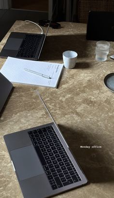 two open laptops sitting on top of a table next to each other with coffee cups