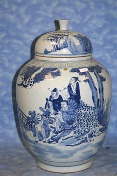 a large blue and white vase sitting on top of a table next to a wall