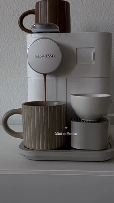 coffee being poured into a cup in front of a coffee maker on top of a counter