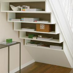 a white book shelf sitting under a stair case