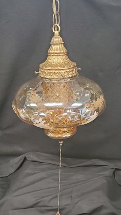 an antique brass hanging light fixture on a black background