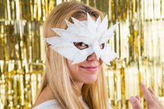 a woman wearing a white mask with flowers on it's face and her hand in the air