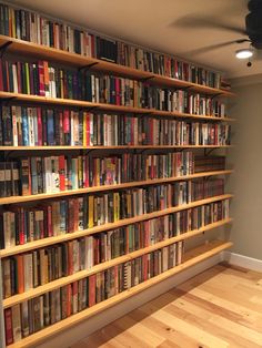 a bookshelf filled with lots of books on top of a hard wood floor