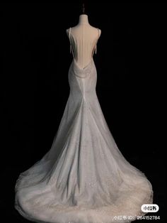 the back of a white wedding dress on a mannequin head stand in front of a black background