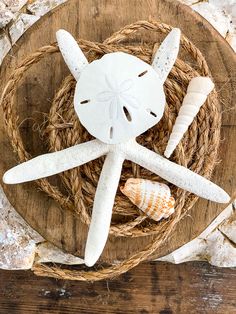 two starfishs and one seashell are sitting on a piece of driftwood