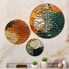 three circular metal artwork pieces hanging on a wall next to a vase and potted plant