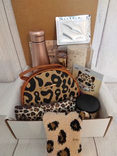 the contents of a leopard print purse sitting in a white box on top of a wooden table