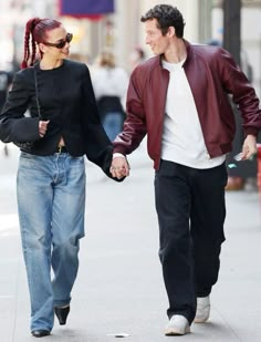 a man and woman walking down the street holding hands