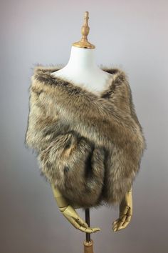 a mannequin wearing a fur vest on top of a wooden stand with two hands