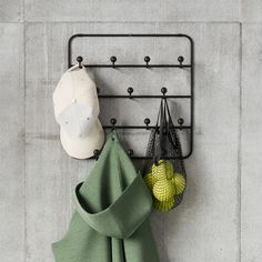 two hats and one green towel hanging on a rack next to a wall mounted hat rack