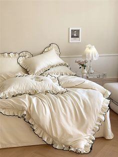 a bed with white sheets and black ruffles