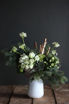 a vase filled with white flowers and greenery