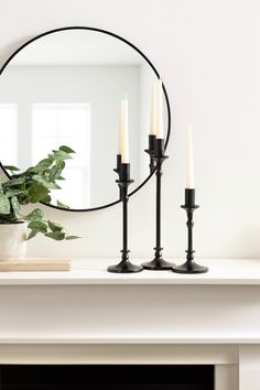 a mirror sitting on top of a mantle next to a potted plant and candles