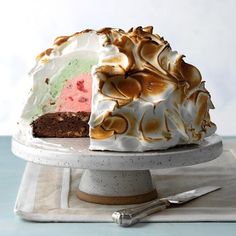 a cake with white frosting and colorful toppings on a plate next to a knife